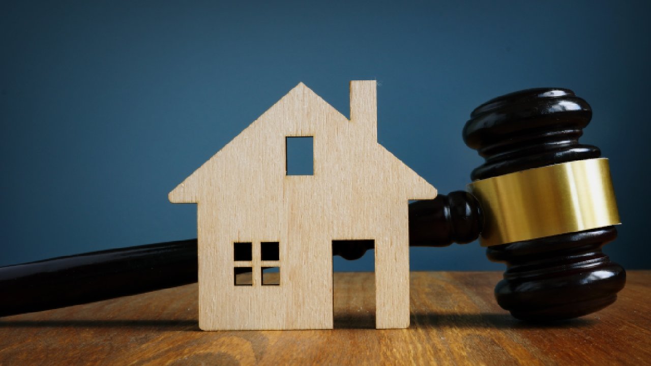 Wooden house on desk next to gavel