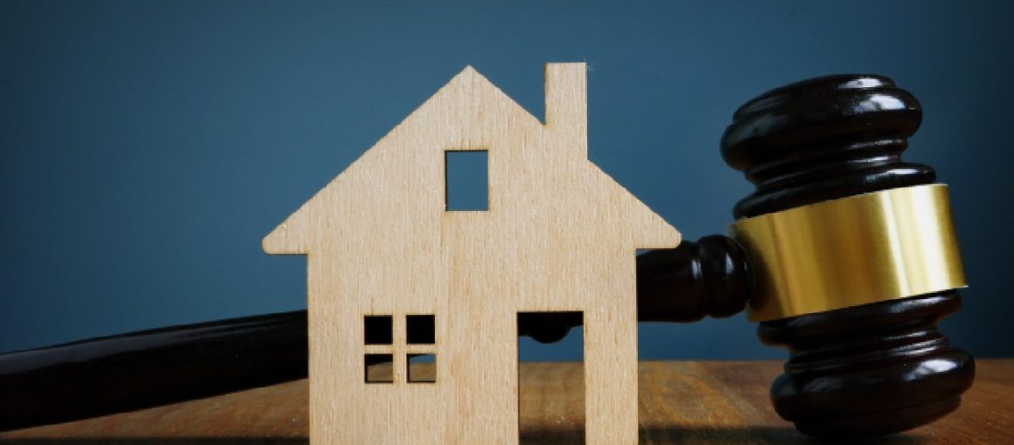 Wooden house on desk next to gavel